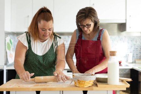Téléchargez les photos : Curvy jeune femme et mère passer du temps ensemble à la maison tout en préparant la nourriture ensemble pour la journée de la famille - en image libre de droit