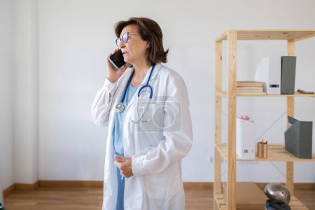 Téléchargez les photos : Femme médecin senior parlant à une patiente au téléphone consultation télématique - en image libre de droit