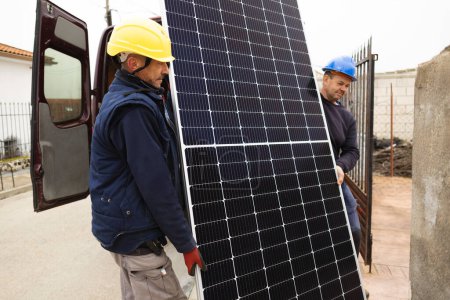 Foto de Trabajadores que transportan paneles solares para su instalación - Imagen libre de derechos
