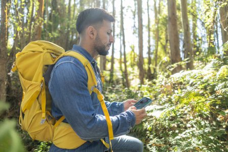 backpacker hiker man lost in the forest looking at his gps map on mobile