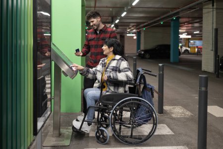 Foto de Mujer en silla de ruedas y hombres pagando en aparcamiento subterráneo - Imagen libre de derechos