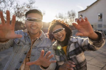 Foto de Amigos multiétnicos con gafas de realidad virtual jugando videojuegos en la calle haciendo gestos con las manos - Imagen libre de derechos