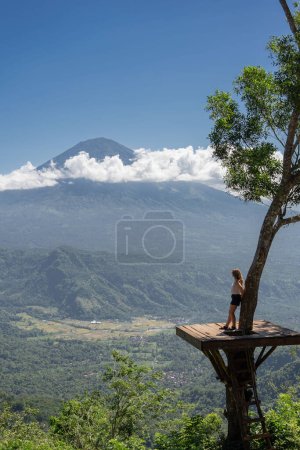 Photo for Young woman traveller enjoy her vacation on Bali island, stand in the field viewpoint with Agung volcano. - Royalty Free Image