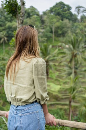 Foto de Una vista trasera de la mujer disfrutando de la vista de los campos de arroz verde. Ubud. Bali, Indonesia . Concepto de viaje. - Imagen libre de derechos
