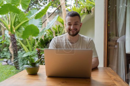 Photo for Young man using a laptop computer in a garden . business, study, freelance - Royalty Free Image