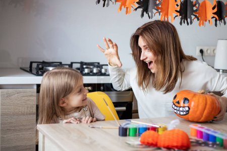 Photo for Mother and little daughter playing and having fun during Halloween preparation at home. - Royalty Free Image