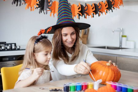 Téléchargez les photos : Mère et petite fille jouant et s'amusant pendant la préparation d'Halloween à la maison. - en image libre de droit