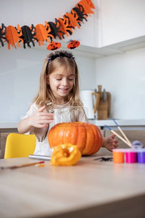 Téléchargez les photos : Enfant sculpter citrouille. Amusant Halloween effrayant. Lanterne Jack o de coupe d'enfant pour la décoration traditionnelle de tour ou de traiter - en image libre de droit