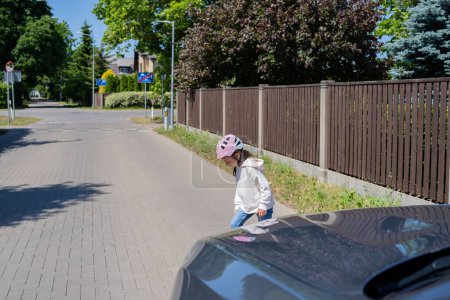 Téléchargez les photos : Un accident. Petite fille sur le skateboard traverse la route devant une voiture. - en image libre de droit