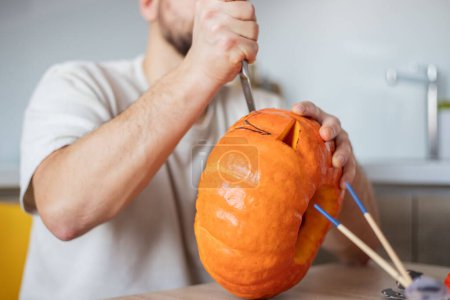 Photo for Hollowing out a pumpkin to prepare halloween lantern. Man carving pumpkin - Royalty Free Image