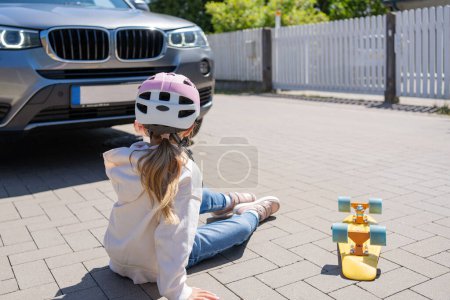 Téléchargez les photos : Fille sur le skateboard a été frappé par la voiture. Le concept d'accidents de la route et la réduction des accidents dus à l'utilisation de voitures sur la route. - en image libre de droit