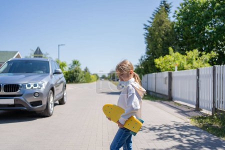 Téléchargez les photos : Fille avec skateboard traversant la route, ne regardant pas la voiture - en image libre de droit