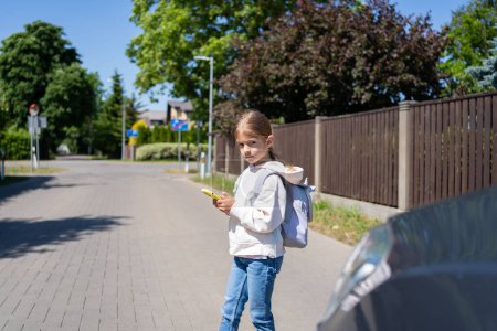 Foto de El niño mira un teléfono celular mientras cruza una calle frente al automóvil. Concepto de adicción al teléfono móvil. - Imagen libre de derechos