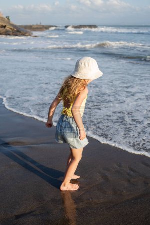 Photo for Young girl jumping and running waves at beach on sunset time - Royalty Free Image
