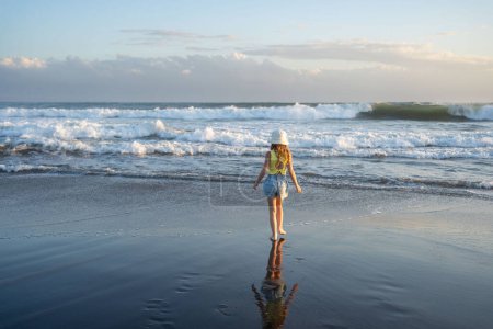 Foto de Chica joven saltando y corriendo olas en la playa en la hora de la puesta del sol - Imagen libre de derechos
