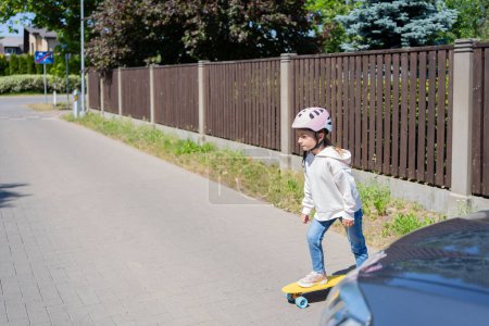 Photo for Accident. Small girl on the skateboard crosses the road in front of a car. - Royalty Free Image