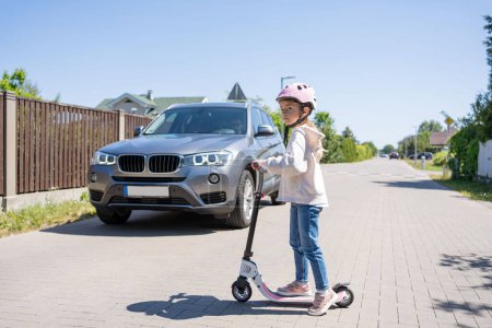 Téléchargez les photos : Un accident. Petite fille sur le scooter rouler et traverse la route devant une voiture. - en image libre de droit
