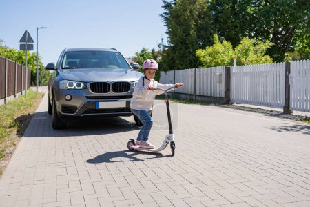 Téléchargez les photos : Un accident. Petite fille sur le scooter rouler et traverse la route devant une voiture. - en image libre de droit