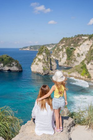 Téléchargez les photos : Vue arrière enfant et femme sur le bord d'une falaise regardant Diamond beach, Nusa Penida. Vue panoramique de Diamond Beach à Nusa Penida Bali, Indonésie. - en image libre de droit