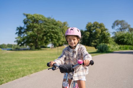 Photo for Cheerful child rides on a Bicycle in city park outdoor. - Royalty Free Image