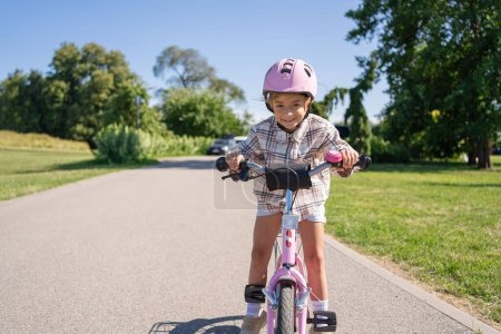 Téléchargez les photos : Enfants joyeux promenades sur un vélo dans le parc de la ville en plein air. - en image libre de droit