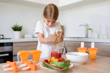 Photo for Portrait of cute child girl making ice cream. Kid have fun making with homemade fruit puree ice cream. Home made ice lollies. High quality photo - Royalty Free Image