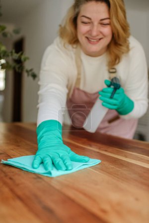 Foto de Limpieza de la mesa de la casa desinfectante superficie de la mesa de la cocina con desinfectante spray botella lavado superficies con toalla y guantes - Imagen libre de derechos