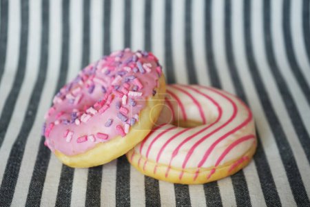 Foto de Donuts con glaseado rosa sobre fondo rayado - Imagen libre de derechos