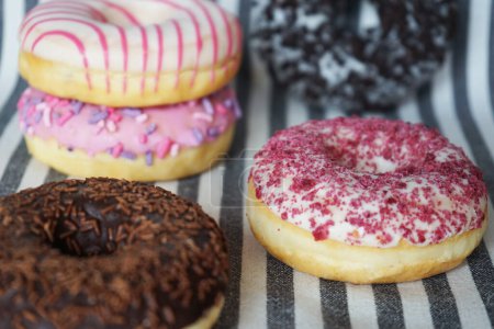 Foto de Donuts con glaseado rosa y chocolate sobre fondo rayado - Imagen libre de derechos