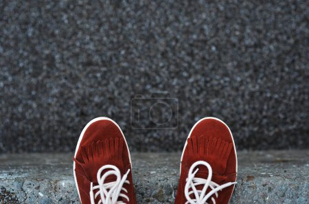 Foto de Zapatillas de deporte de gamuza roja en un muelle de piedra sobre un fondo de pequeñas piedras - Imagen libre de derechos