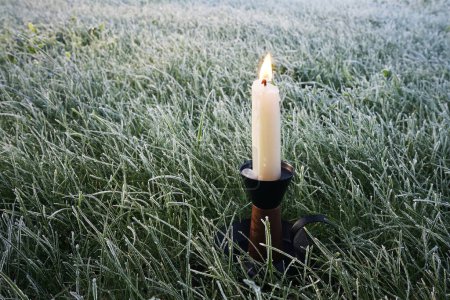 Foto de Vela ardiendo en un candelero en la hierba congelada - Imagen libre de derechos