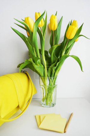 Yellow tulips next to yellow stickers and a yellow bag on a white background