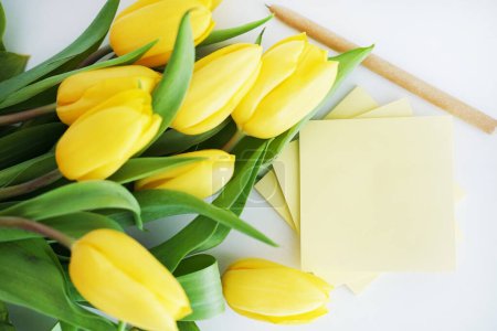 Yellow tulips next to yellow stickers on a white background