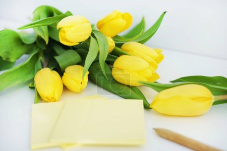 Yellow tulips next to yellow stickers on a white background