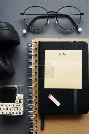 Bloc-notes à côté du stylo, notes collantes, lunettes, smartphone et écouteurs sur fond gris