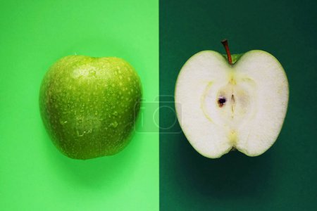 Téléchargez les photos : Moitiés d'une pomme verte mûre sur fond vert - en image libre de droit