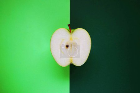 Téléchargez les photos : Une demi-pomme verte mûre sur fond vert - en image libre de droit