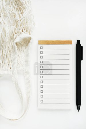 Lista de tareas pendientes junto a bolsa de cuerdas y bolígrafo sobre fondo blanco