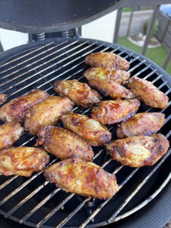 Palitos de pollo marinados picantes que se cocinan sobre las llamas de una barbacoa crujiente la piel para un delicioso picnic de verano. Foto de alta calidad
