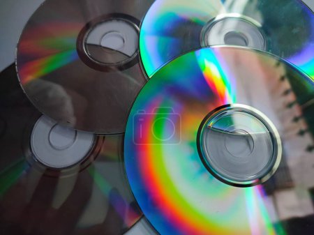 Téléchargez les photos : Les CD qui sont exposés à la lumière et émettent des couleurs colorées sont isolés sur un fond blanc - en image libre de droit