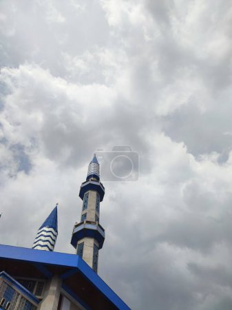The blue dome of the mosque has a background of sky and clouds