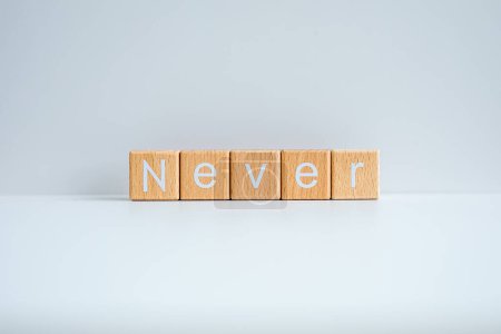 Téléchargez les photos : Les blocs de bois forment le texte "Jamais" sur un fond blanc. - en image libre de droit