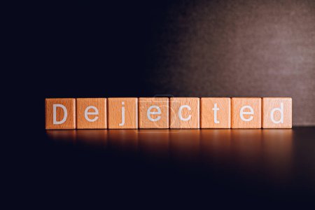 Wooden blocks form the text "Dejected" against a black background.