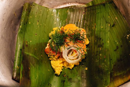 uncooked ingredients of a Colombian tamale on a banana leaf on a wooden table in the kitchen