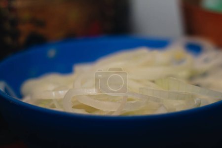 blauer Teller voller großer Zwiebeln in der Küche, um ein köstliches kolumbianisches Tamale zuzubereiten