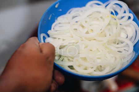 assiette bleue pleine de gros oignon dans la cuisine pour préparer un délicieux tamale colombien
