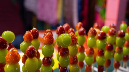 Photo for Pictures of sweet street food menus at temple fairs This menu is fruit skewers. It consists of large green grapes. and small strawberries skewered and drizzled with syrup. - Royalty Free Image