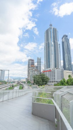 Photo for Modern park walkway, shady atmosphere It is a beautiful cement tiled bridge. urban social scenery You can see the tall buildings reaching into the sky. and concrete road light sky dense clouds - Royalty Free Image