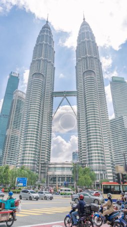 Photo for Twin Towers Petronas Towers in Malaysia Viewed from the corner of the intersection There are a lot of cars parked. Tall buildings shaped like twin rockets, with a walkway connecting the 2 buildings, - Royalty Free Image