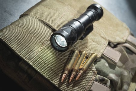 Téléchargez les photos : Une lampe de poche à arme tactique et des munitions de 5,56x45mm. - en image libre de droit